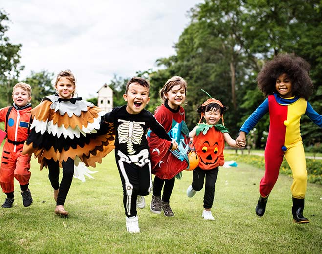 Children running outdoors in Halloween costumes