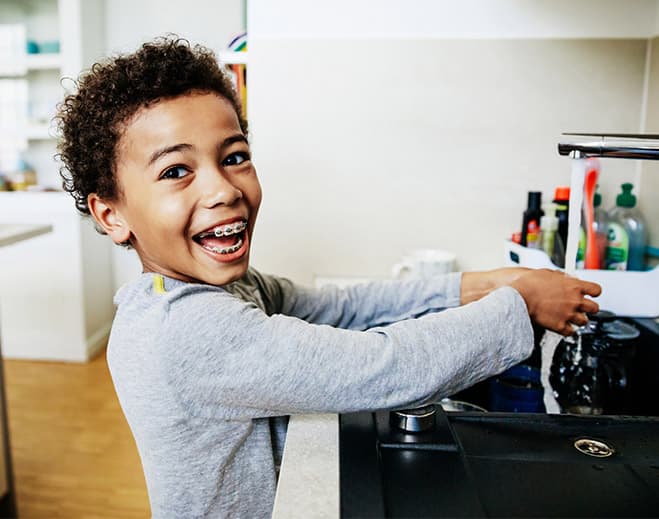 Child washing hands at kitchen sink