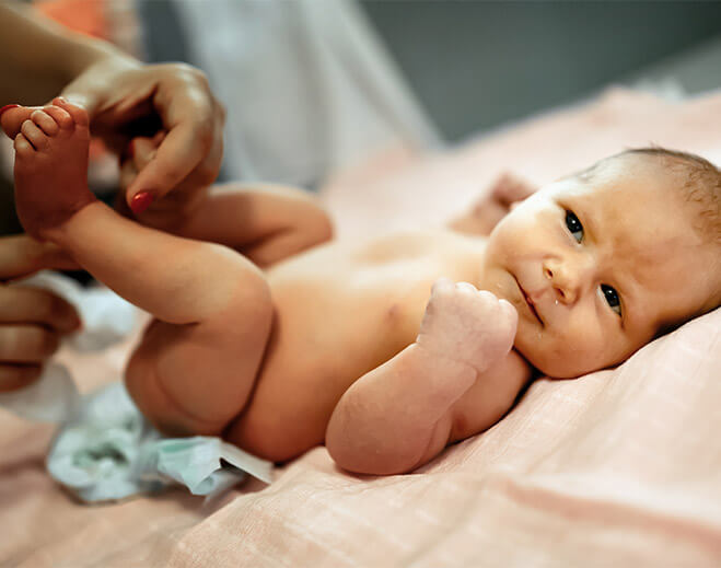 Caregiver changing newborn’s diaper on table