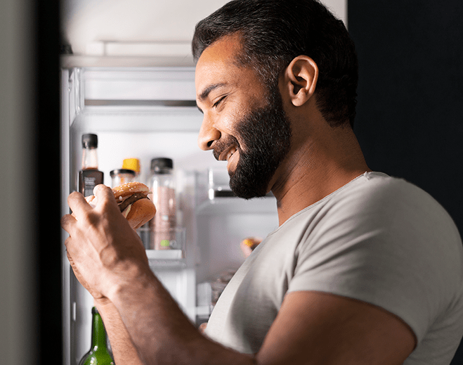 Person holding burger near open fridge