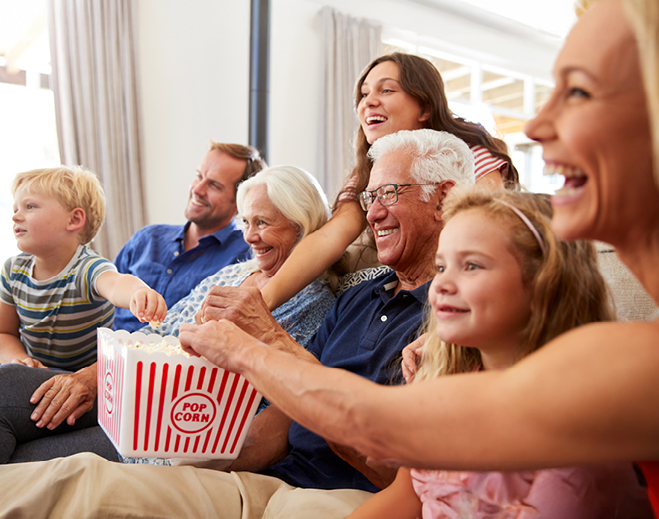 Family watching movie and sharing popcorn