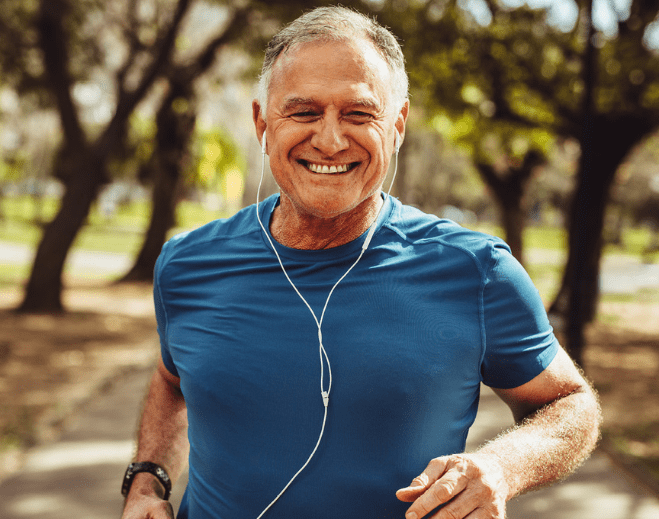 Older adult jogging outdoors with earbuds