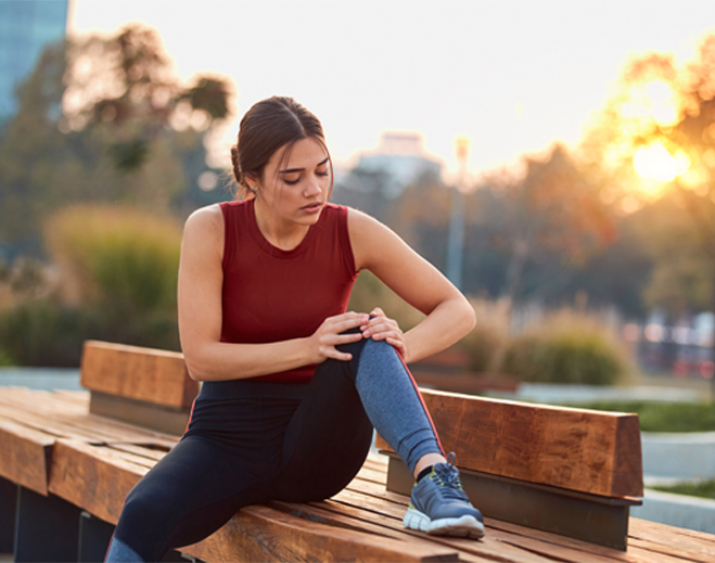 Person holding knee in pain outdoors