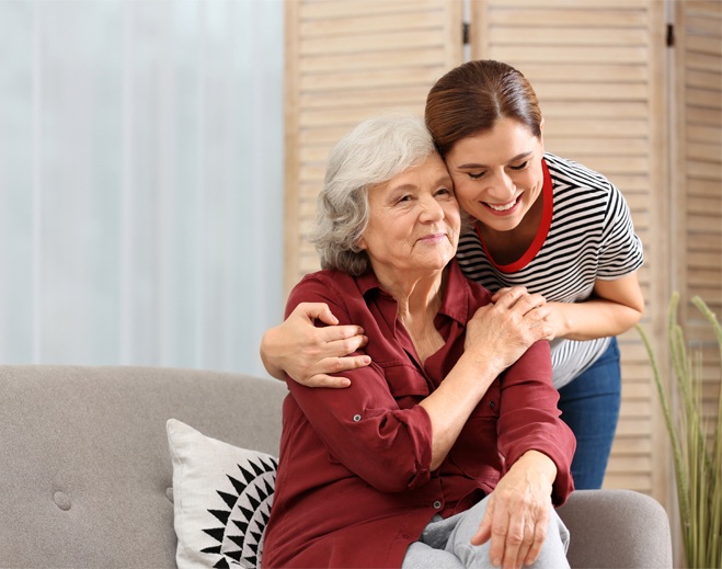 Adult hugging older person on couch