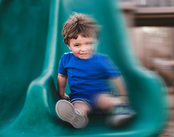 Child sliding down playground slide