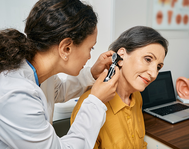 Clinician examining ear with otoscope