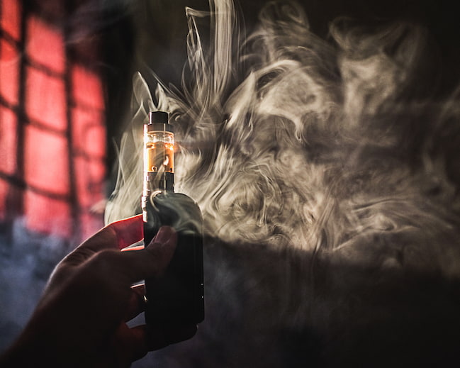 Person holding vape device with smoke