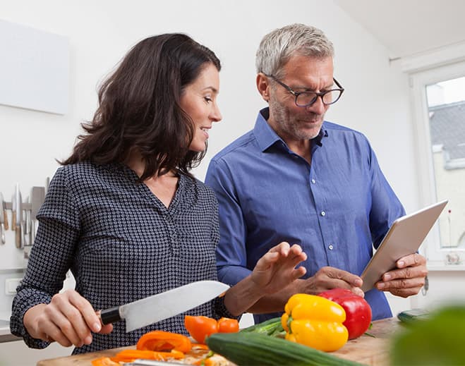 Couple preparing vegetables with tablet recipe