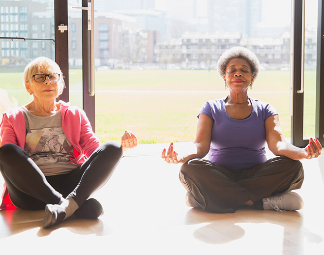 Two people meditating indoors on floor
