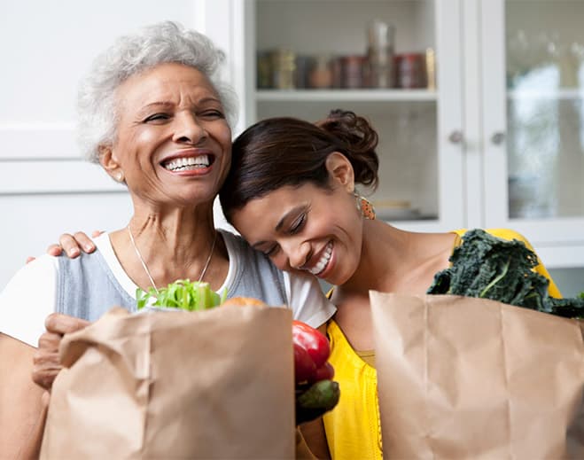 Two people with grocery bags smiling together