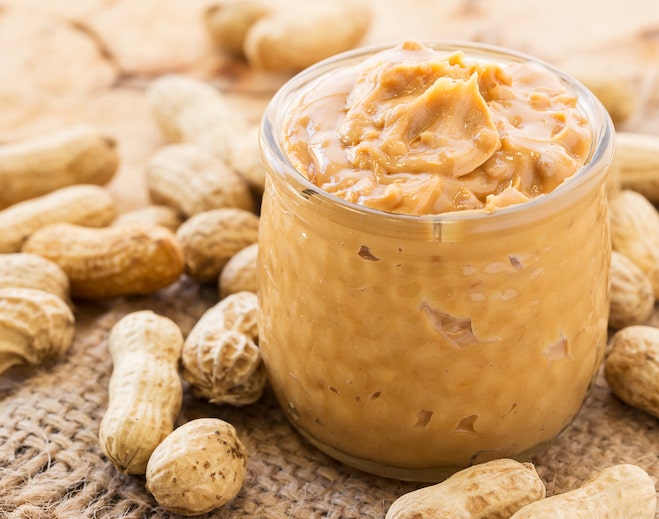 Peanut butter in jar with peanuts