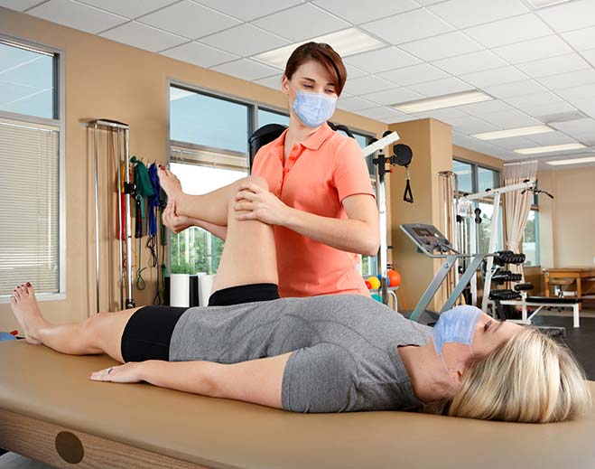 Physical therapist assisting patient leg exercise