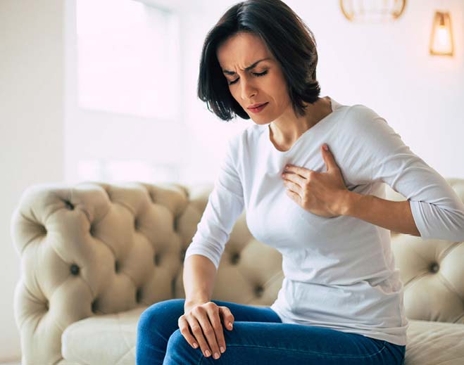 Person holding chest while sitting on couch