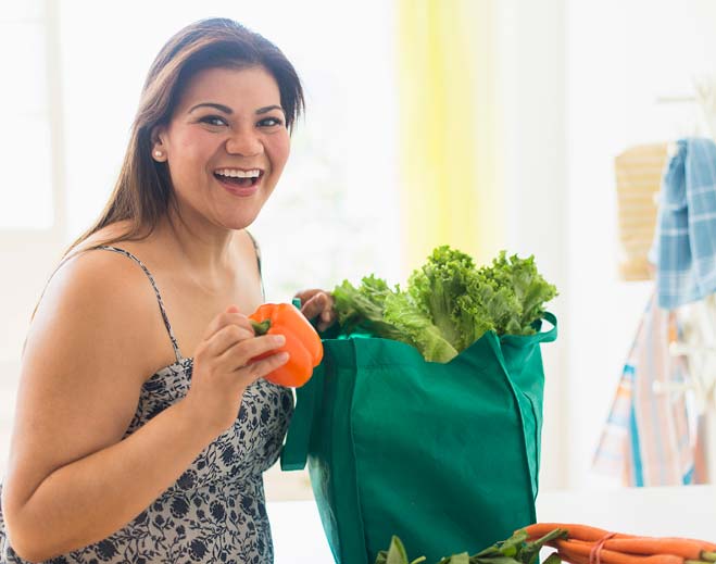 Person carrying groceries with fresh vegetables