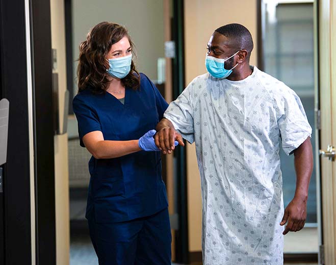 Nurse assisting patient walking in hallway