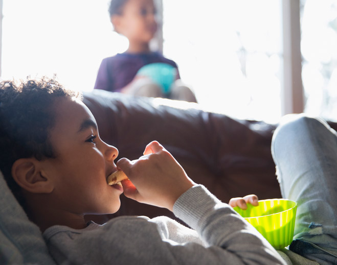 Child eating snack on couch