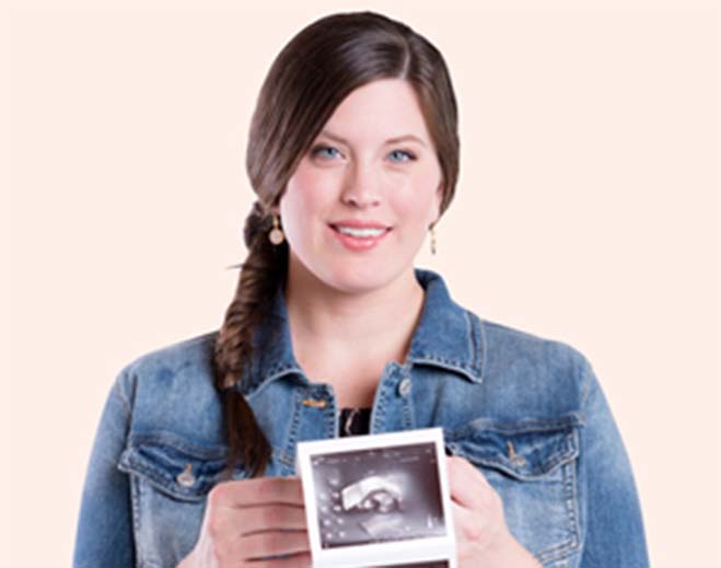 Person holding ultrasound photo of pregnancy