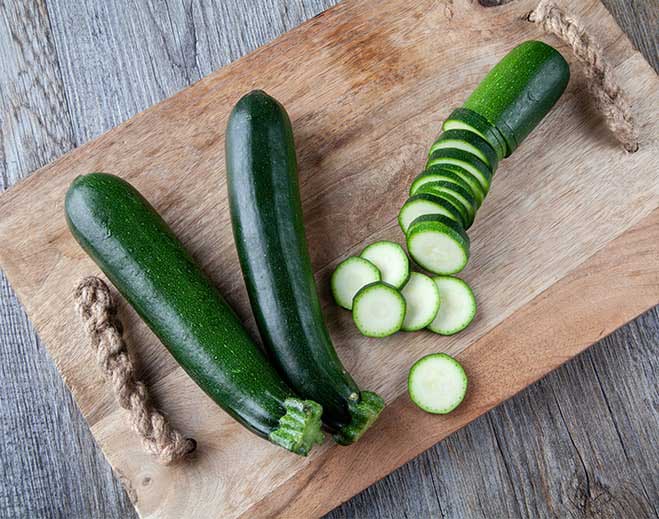 Whole and sliced zucchini on board