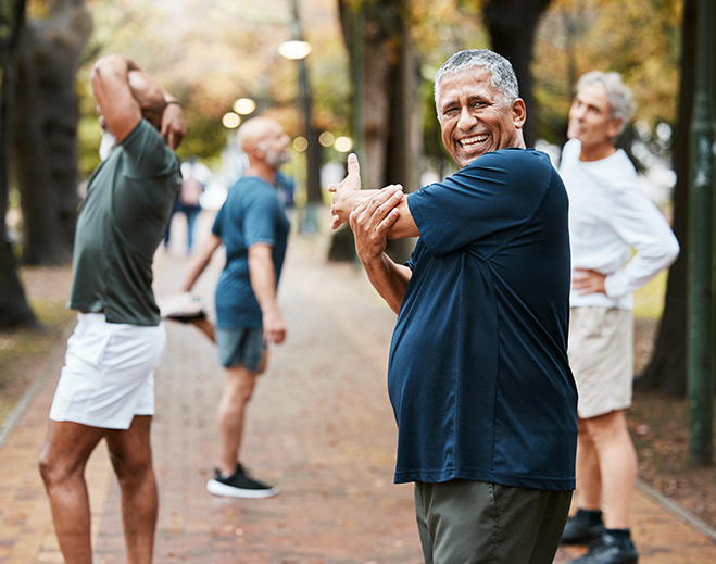 Older adults stretching arms in park