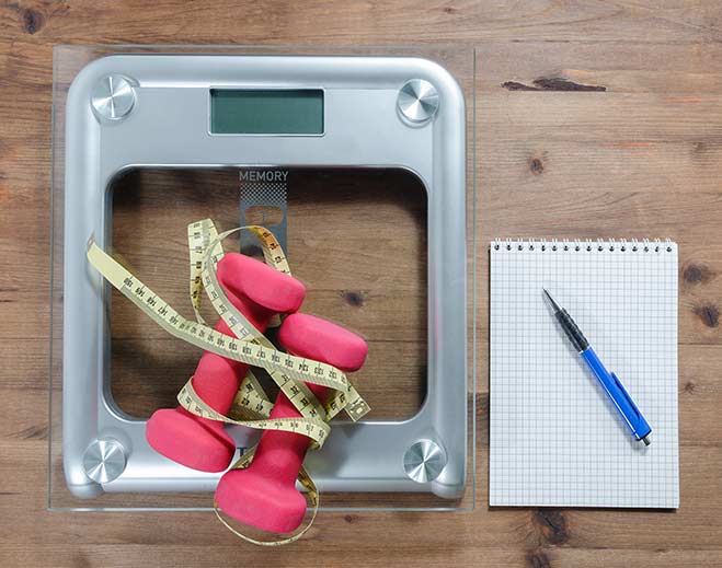 Dumbbells and measuring tape on scale