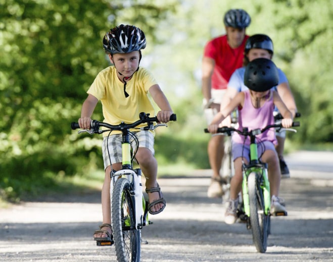 Children riding bikes with helmets outdoors
