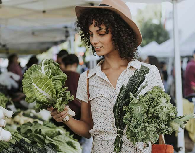 Person choosing leafy greens at market
