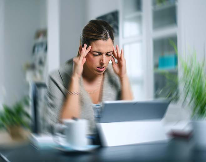 Person holding head while using tablet