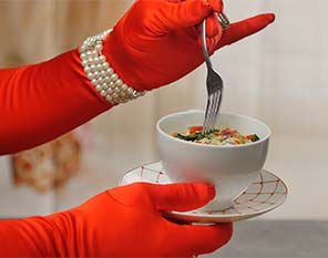 Person holding bowl wearing red gloves