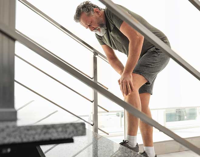 Person holding knee while using stairs