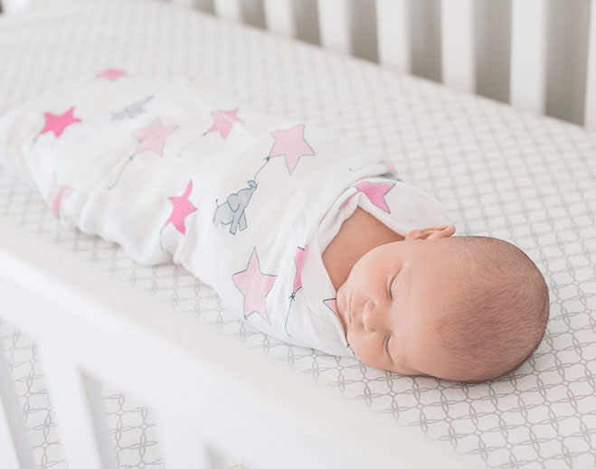 Swaddled baby sleeping in crib