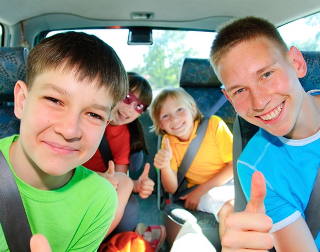 Children smiling in backseat car
