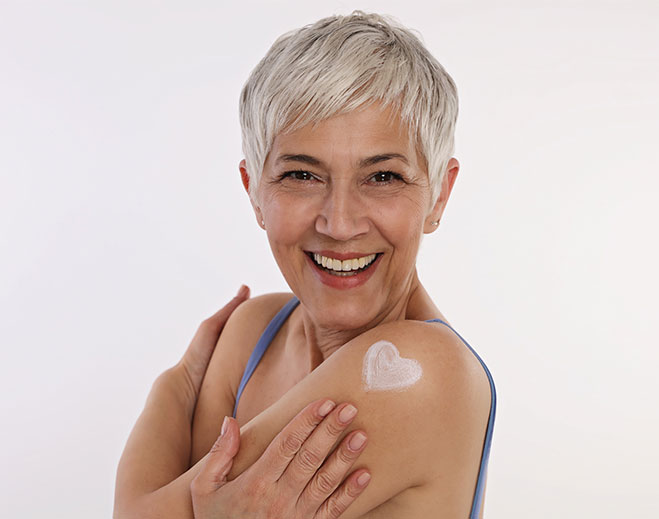 Person applying lotion to shoulder skin