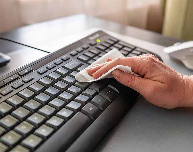 Hand cleaning computer keyboard with wipe