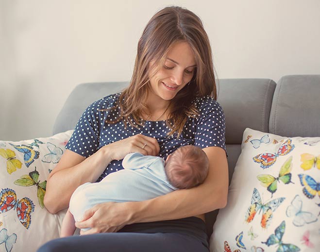 Parent breastfeeding infant on couch