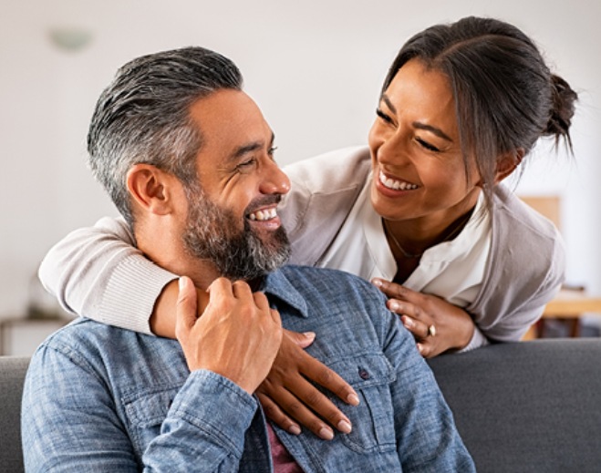 Two adults smiling and sitting together indoors