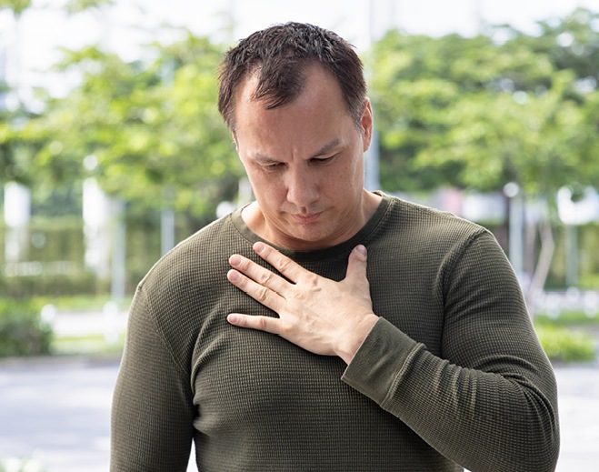 Person holding chest while sitting outside