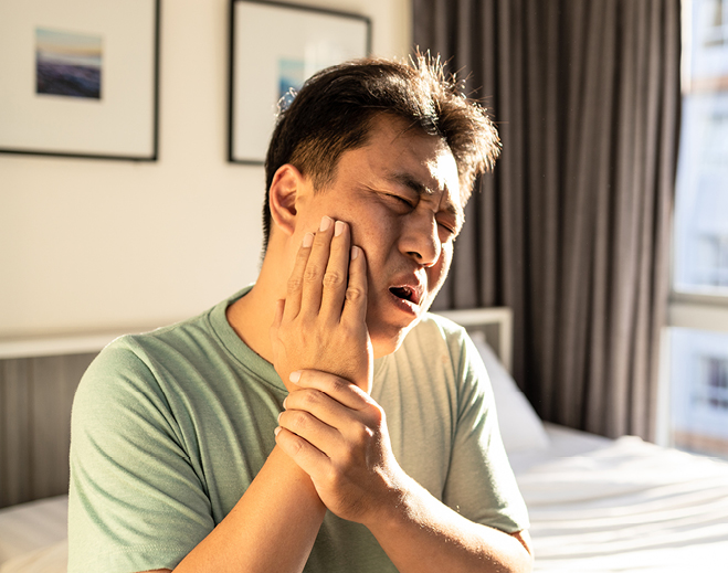 Person touching chest while sitting in bed