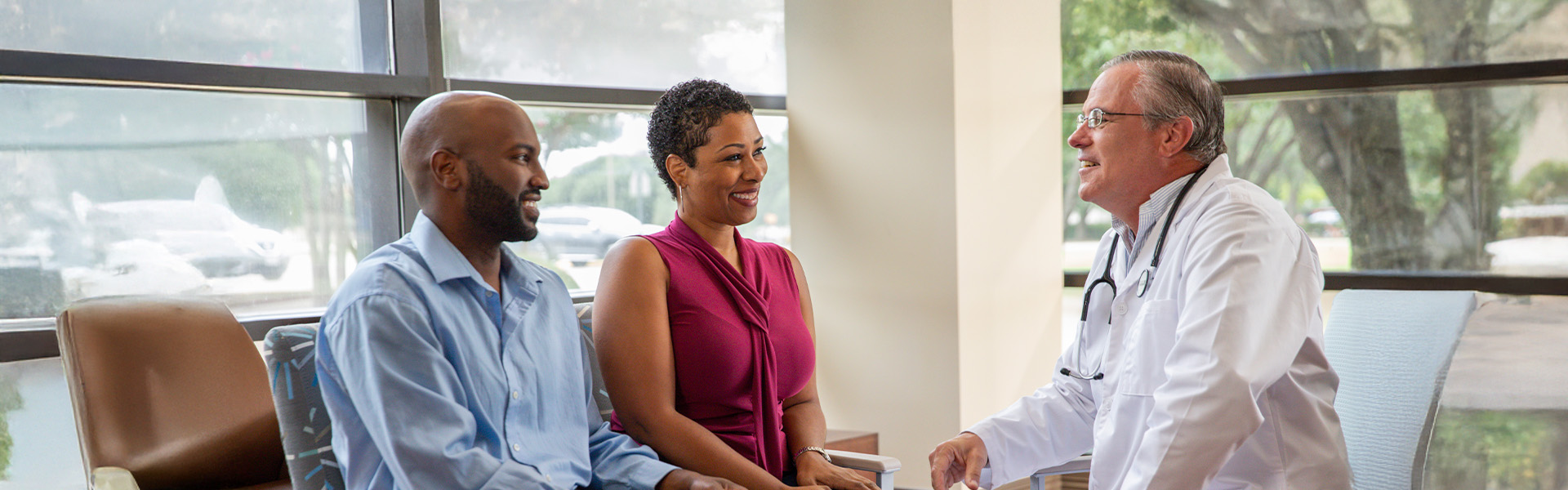 Doctor speaking with two patients in clinic