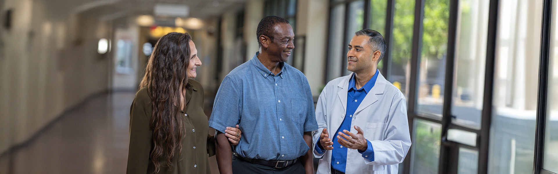couple walking down a hall, talking with physician