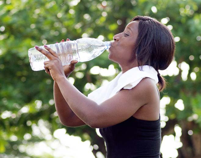 Person drinking water outdoors from bottle