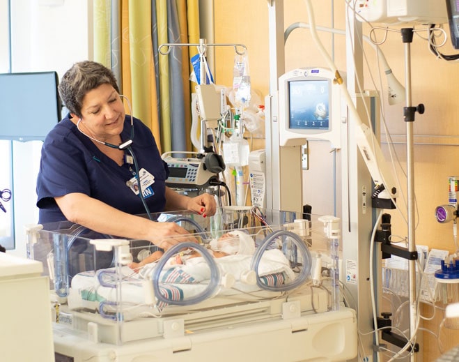 Nurse caring for newborn in incubator