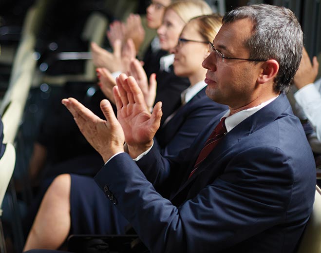 Business audience applauding at event