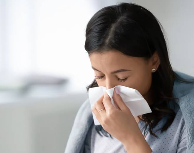 Person blowing nose with tissue