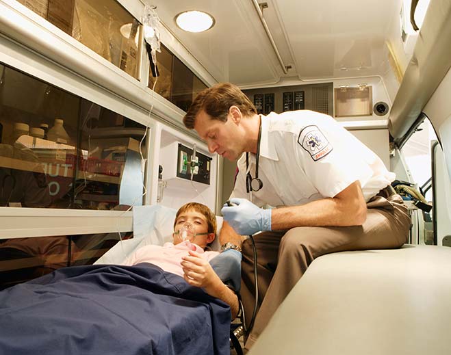 Paramedic treating child in ambulance