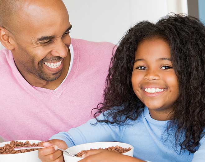 Adult and child eating breakfast together