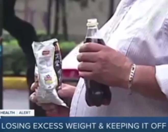 Person holding soda and snack outdoors
