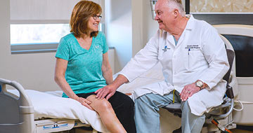 Orthopedic physician checking a woman's knee for pain