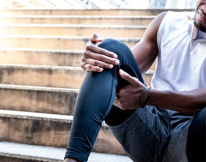 Person holding knee while sitting on stairs