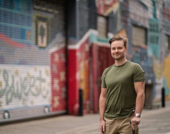 Jake standing in front of colorful mural