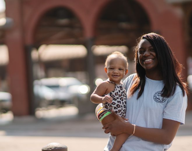Karyha holding baby outdoors in city